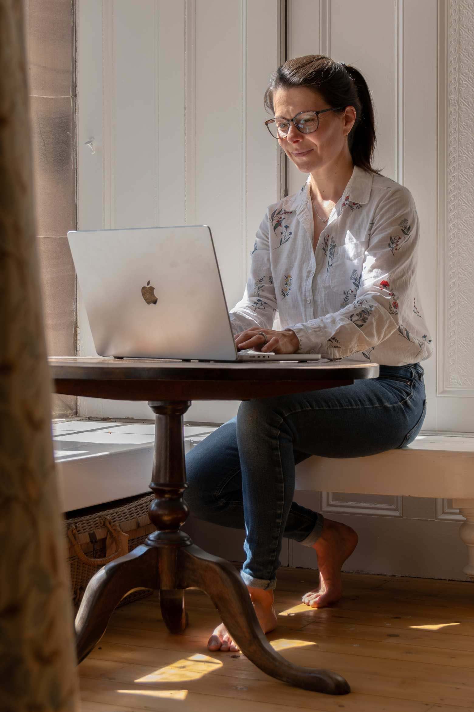 Katie sat at a table having an online meeting with a health coaching client