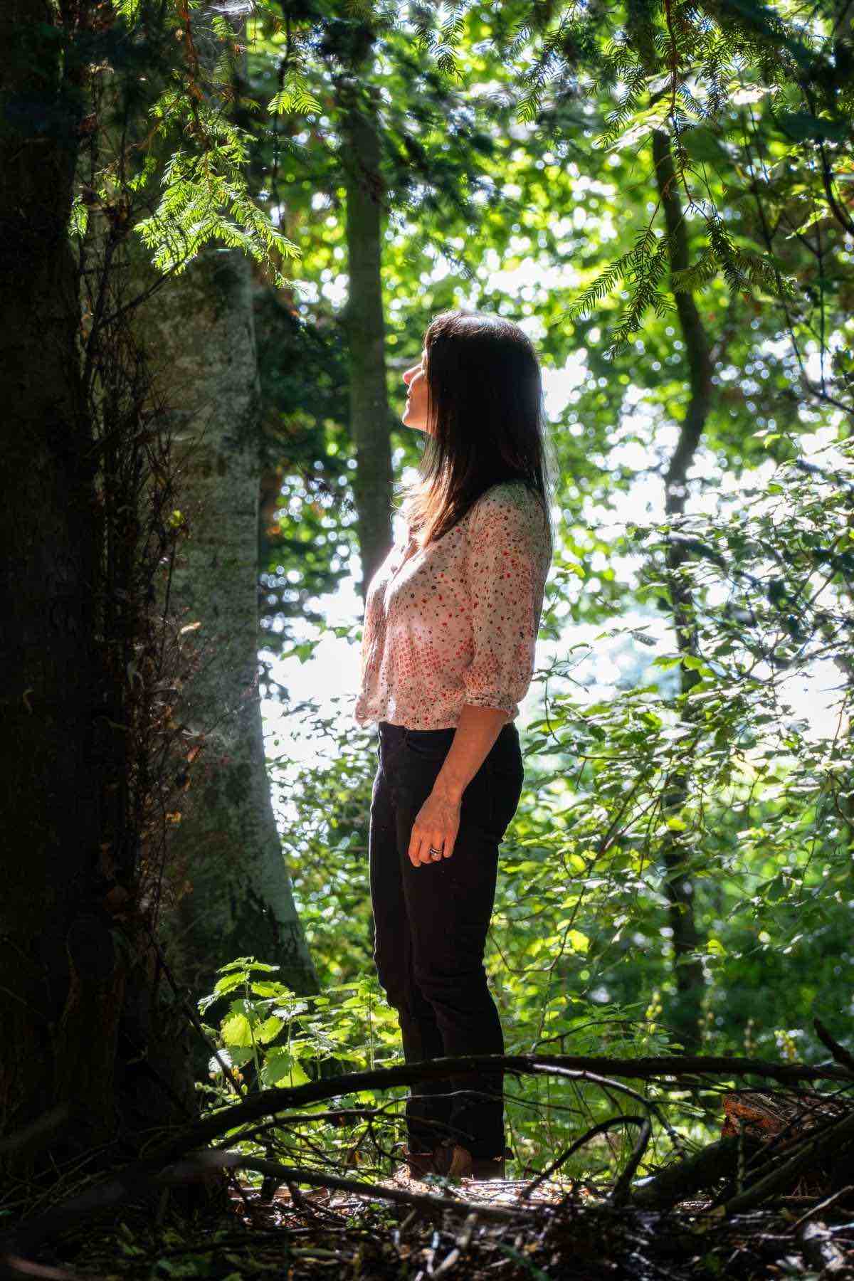 Dr Katie Gillett standing in a woodland, ready to support midlife women who are navigating postpartum and beyond